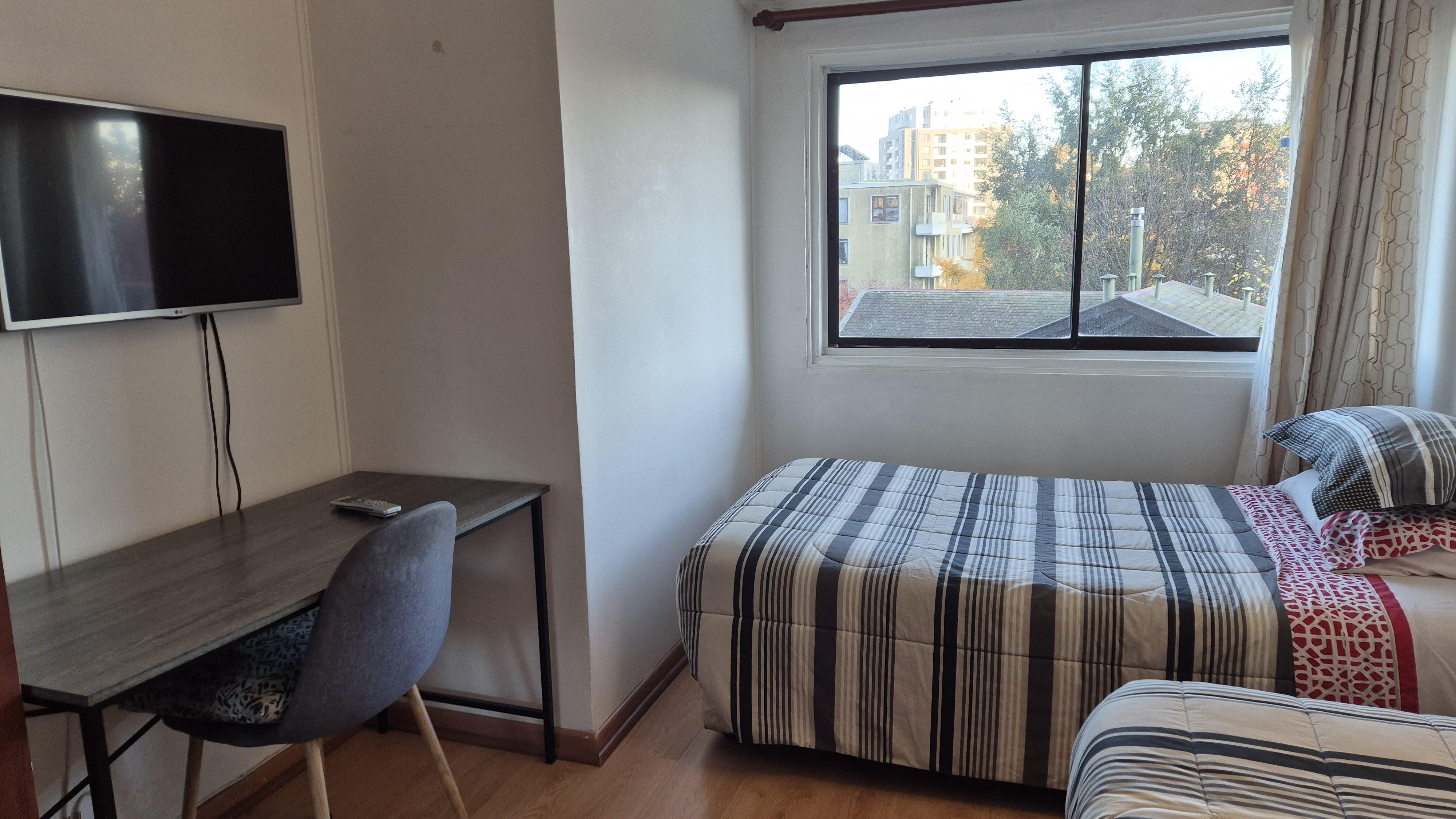 Habitación del hostal con escritorio, TV y vista a Concepción